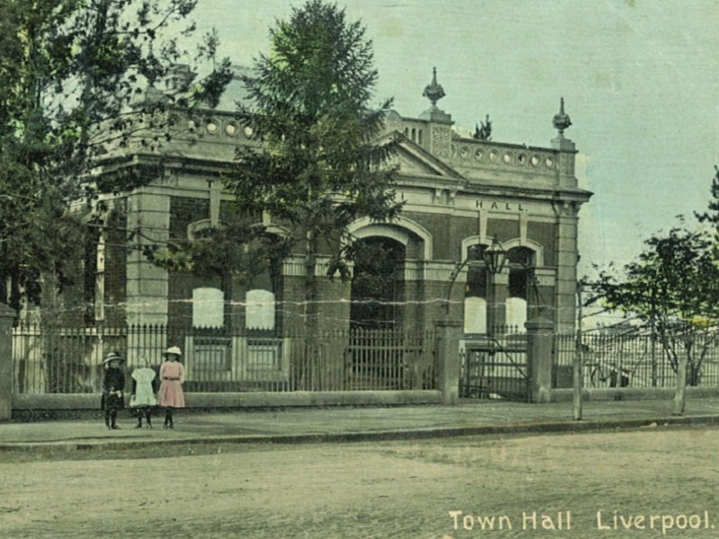 Hand coloured postcard of the Liverpool Town Hall dated from the early 1900s. Liverpool’s first town hall was built in 1881 and was replaced by a new building in 1939. Liverpool City Library Heritage Collection.
