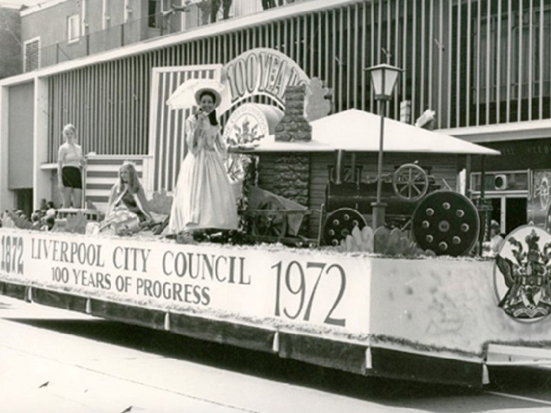 Liverpool City Council float participating in the Liverpool Festival of Progress of 1972 as it moves along Macquarie Street, Liverpool. A banner on the side of the float reads "1872 Liverpool City Council 100 years of progress 1972. Liverpool City Library Heritage Collection.